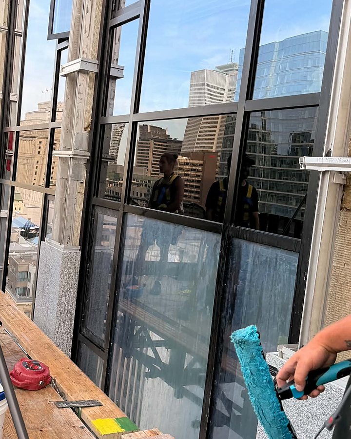 Gros plan d'une mouilleuse OMAX sur la vitre d'une tour au centre-ville, gratte-ciels en arrière-plan