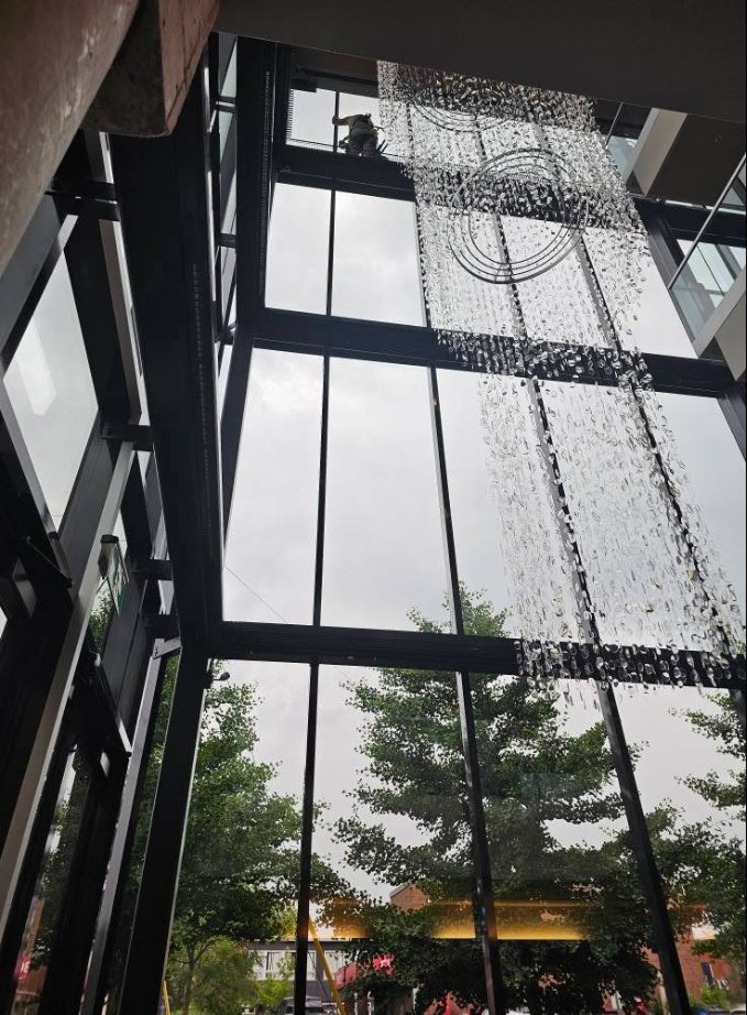 Vue d'un atrium vitré en hauteur pendant le lavage, eau ruisselant sur les vitres