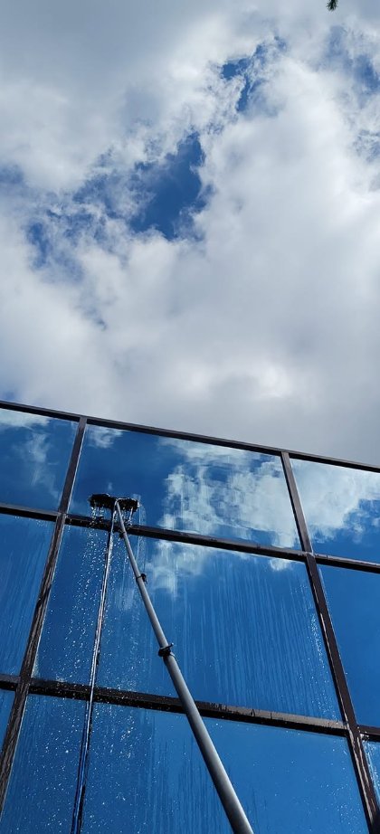 Perche à eau pure en action contre le ciel, rinçage d'une façade vitrée