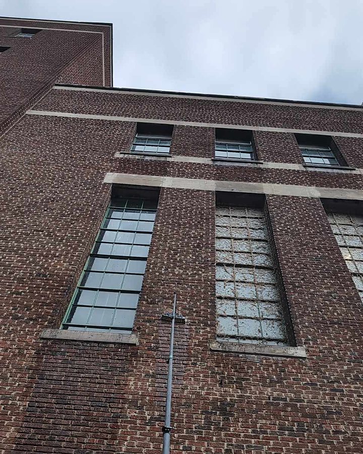 Perche OMAX levée le long d'une façade patrimoniale en brique aux grandes fenêtres à carreaux