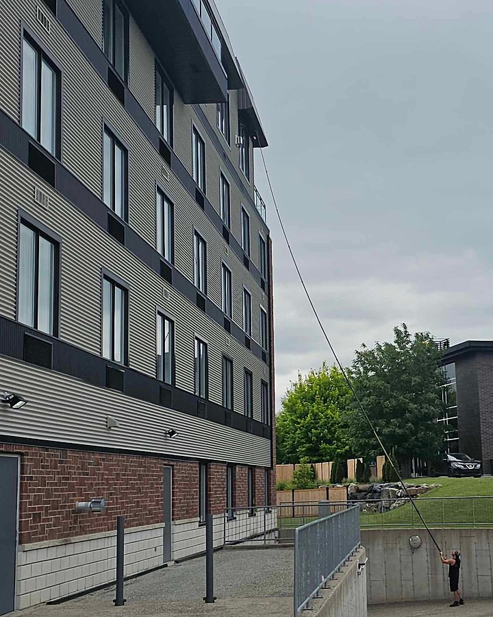 Technicien OMAX lavant un immeuble à logements de cinq étages à la perche à eau pure