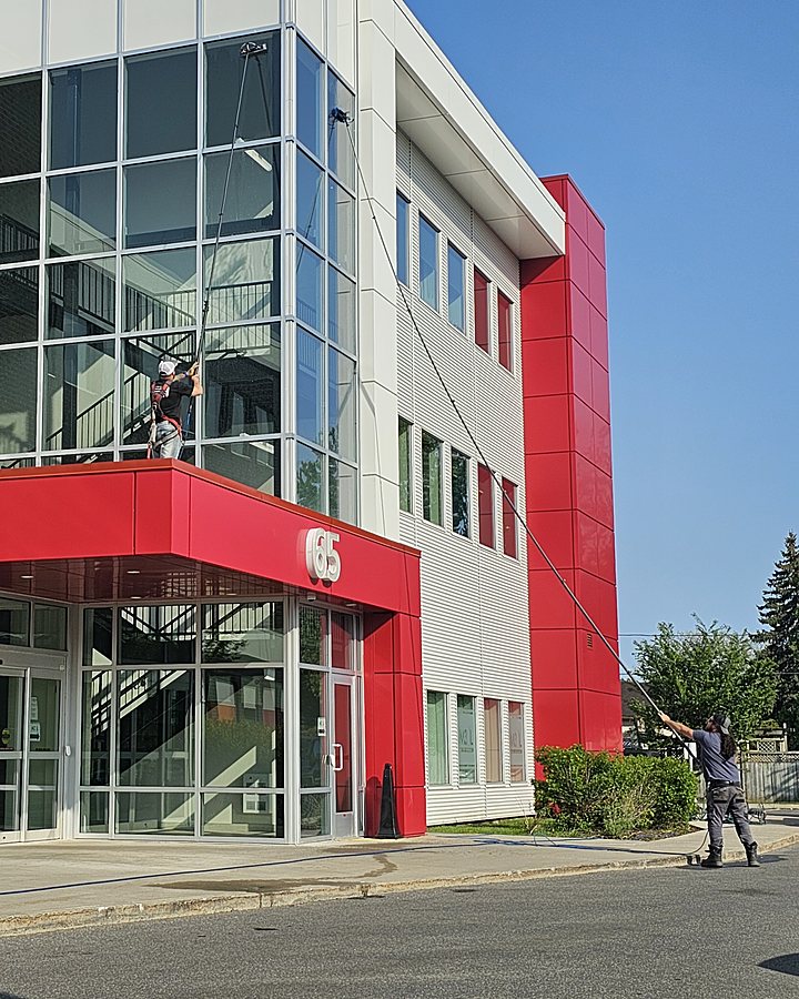 Technicien OMAX lavant la verrière d'un édifice à bureaux au centre-ville
