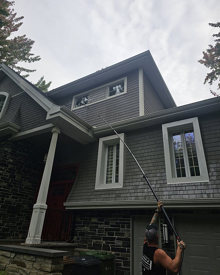 Technicien OMAX lavant les fenêtres du deuxième étage d'une maison avec une perche à eau pure