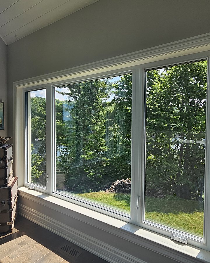 Grande baie vitrée de salon parfaitement transparente après le lavage OMAX, vue sur la forêt