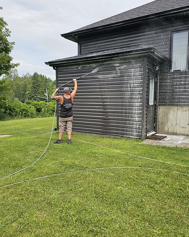 Technicien OMAX nettoyant à pression le revêtement extérieur d'une maison